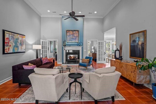 living room featuring crown molding, dark tile patterned flooring, a towering ceiling, and ceiling fan