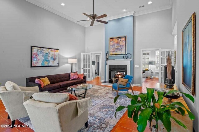 tiled living room featuring ornamental molding, ceiling fan, and a towering ceiling