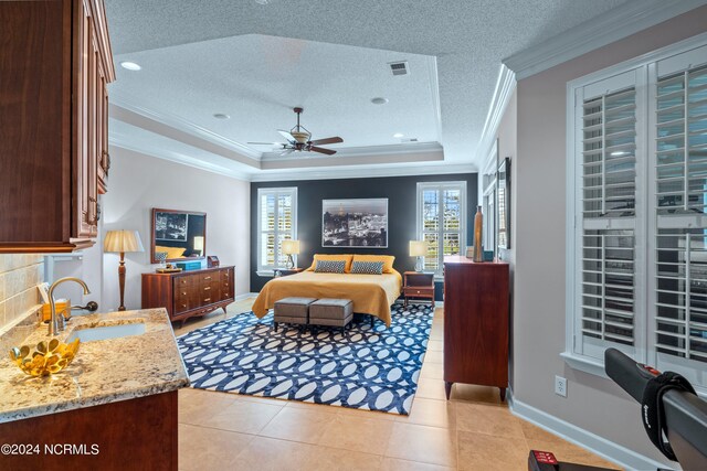 bedroom featuring multiple windows, a tray ceiling, a textured ceiling, and sink