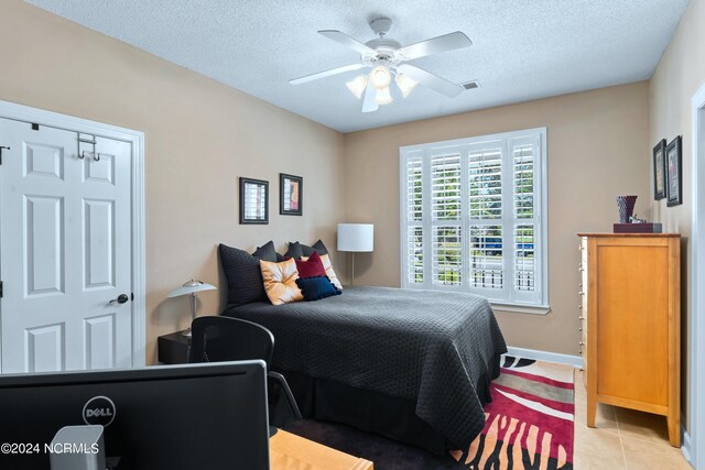 tiled bedroom featuring a textured ceiling and ceiling fan