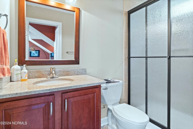 bathroom with an enclosed shower, toilet, and vanity