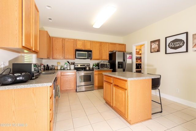 kitchen featuring light tile patterned flooring, sink, a breakfast bar area, a center island, and stainless steel appliances