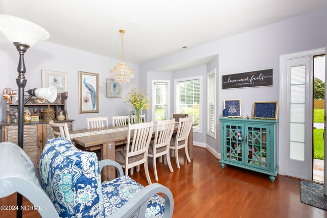 dining space with dark hardwood / wood-style floors and a notable chandelier