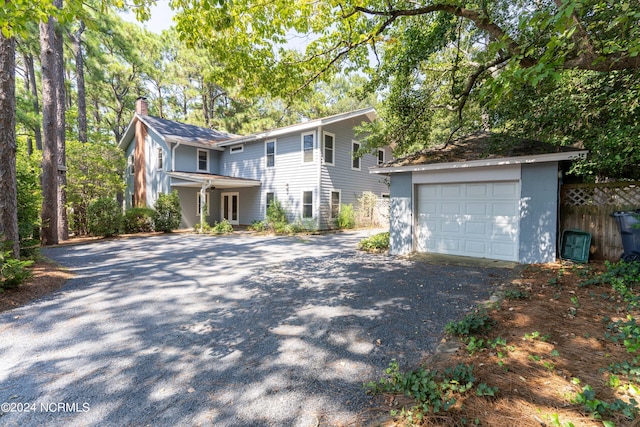 view of front of house with aphalt driveway, a garage, an outdoor structure, fence, and a chimney