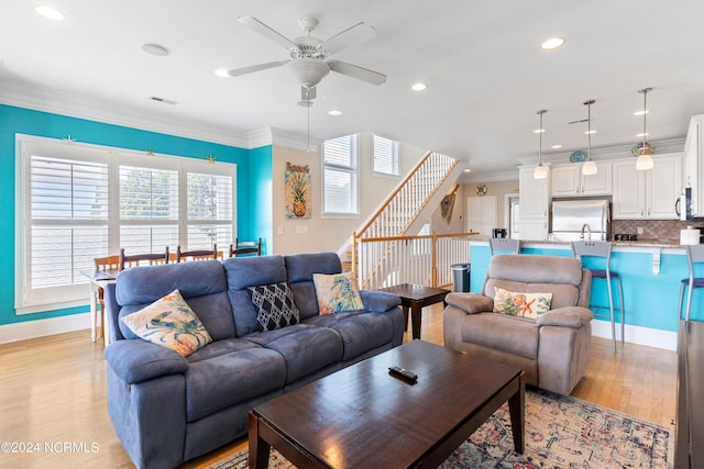 living room with light hardwood / wood-style flooring, ornamental molding, and ceiling fan