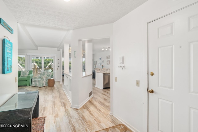 corridor featuring light wood-type flooring and a textured ceiling