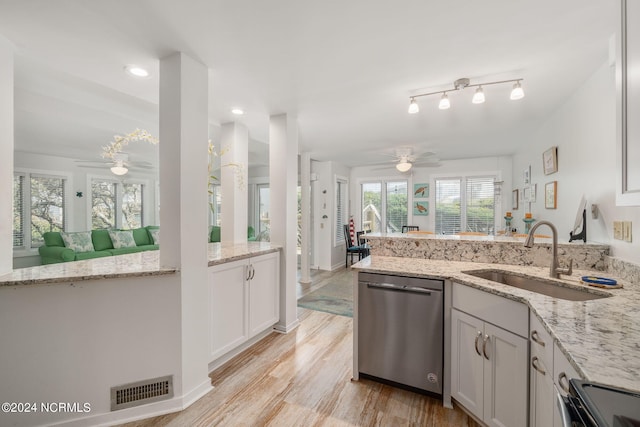 kitchen featuring stainless steel dishwasher, white cabinets, and light stone counters