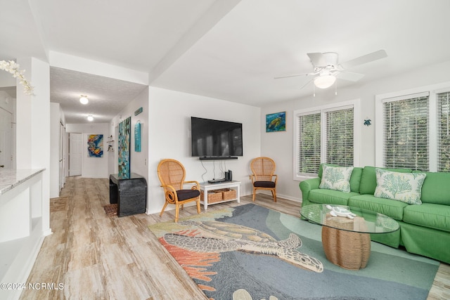 living room with ceiling fan, light hardwood / wood-style floors, and a textured ceiling