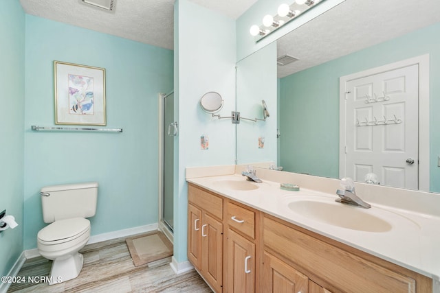 bathroom featuring vanity, a shower with shower door, toilet, a textured ceiling, and wood-type flooring