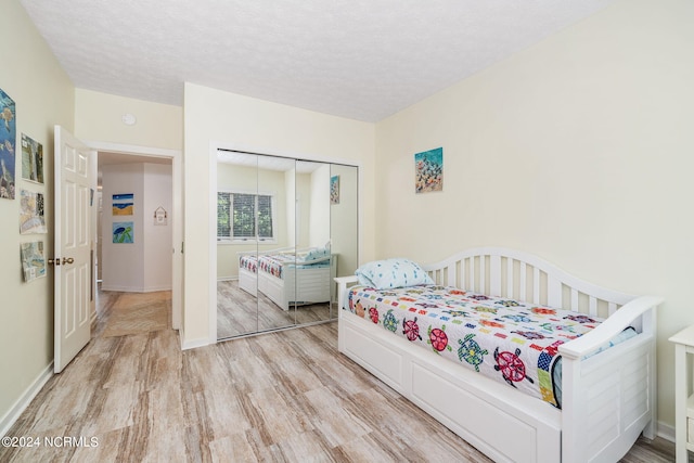 bedroom featuring a textured ceiling, light hardwood / wood-style flooring, and a closet