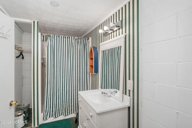 bathroom featuring vanity, a shower, and a textured ceiling