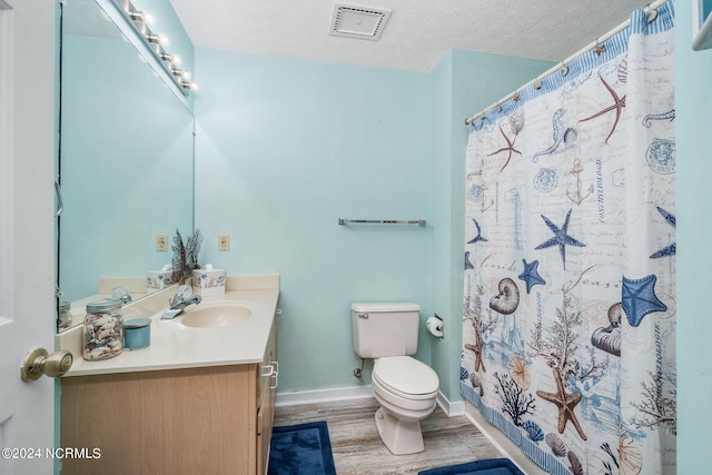 bathroom with walk in shower, vanity, a textured ceiling, hardwood / wood-style floors, and toilet