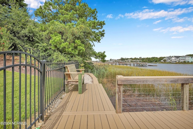 deck featuring a gate, a water view, fence, and a lawn