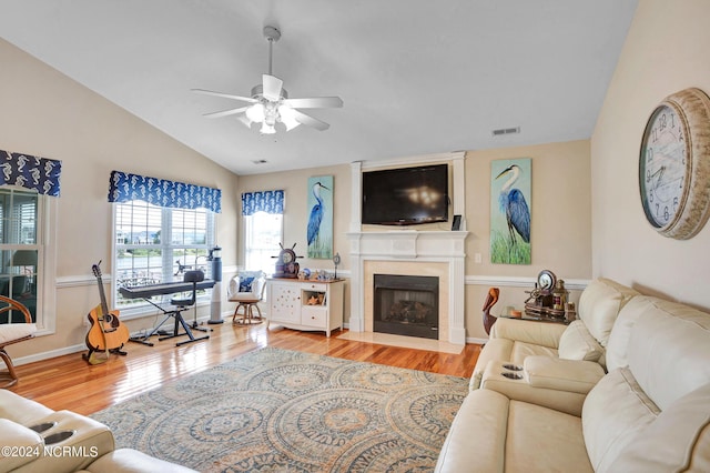 living room featuring ceiling fan, a fireplace with flush hearth, wood finished floors, visible vents, and vaulted ceiling