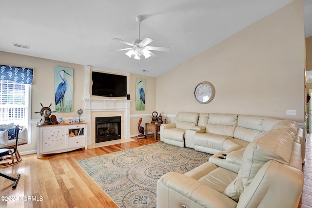 living area with visible vents, lofted ceiling, light wood-style flooring, ceiling fan, and a high end fireplace