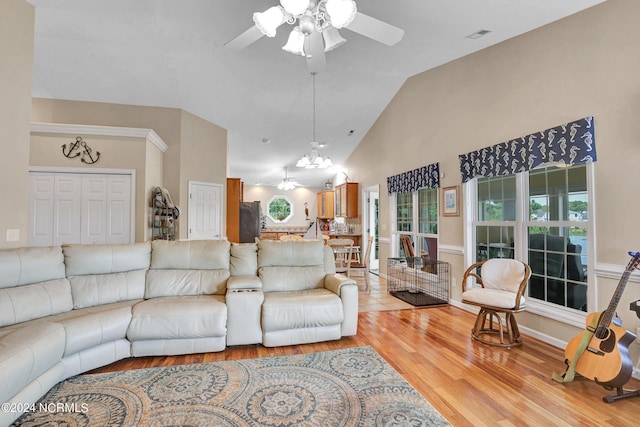 living area with light wood finished floors, high vaulted ceiling, and ceiling fan with notable chandelier