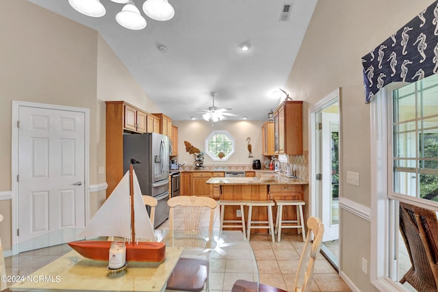 kitchen featuring a breakfast bar, sink, appliances with stainless steel finishes, light tile patterned floors, and kitchen peninsula