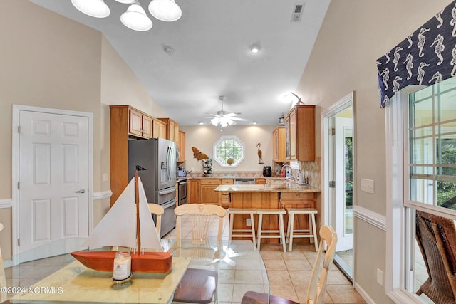 kitchen with light tile patterned floors, a peninsula, brown cabinets, and stainless steel appliances