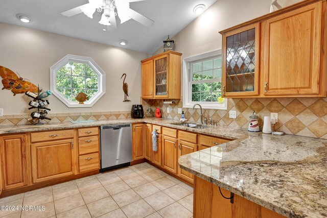 kitchen with ceiling fan, stainless steel dishwasher, backsplash, light stone counters, and sink