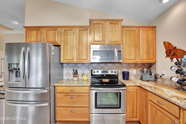 kitchen featuring light stone counters, lofted ceiling, recessed lighting, backsplash, and appliances with stainless steel finishes