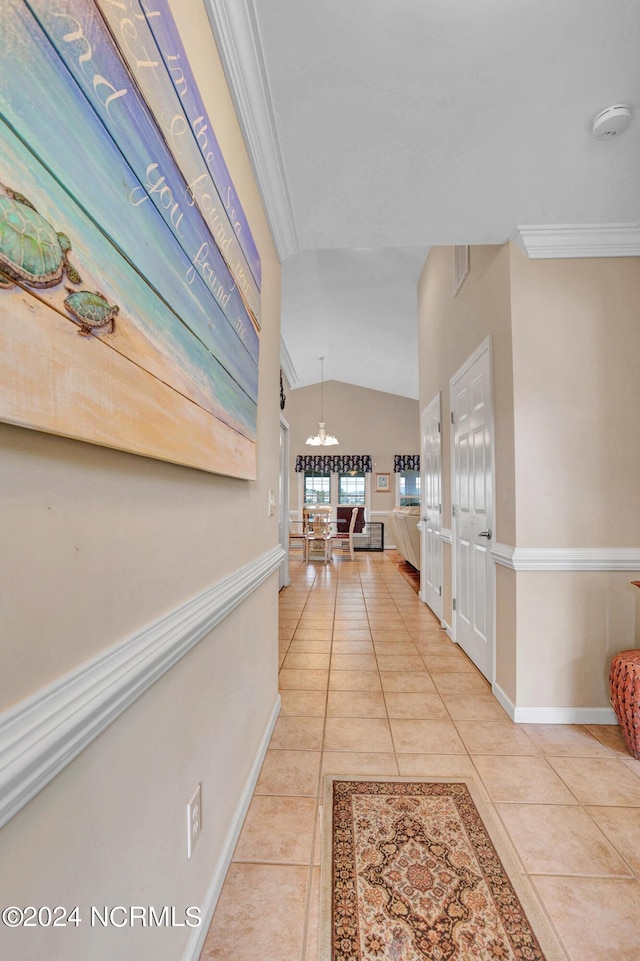 corridor with lofted ceiling, crown molding, baseboards, and light tile patterned floors