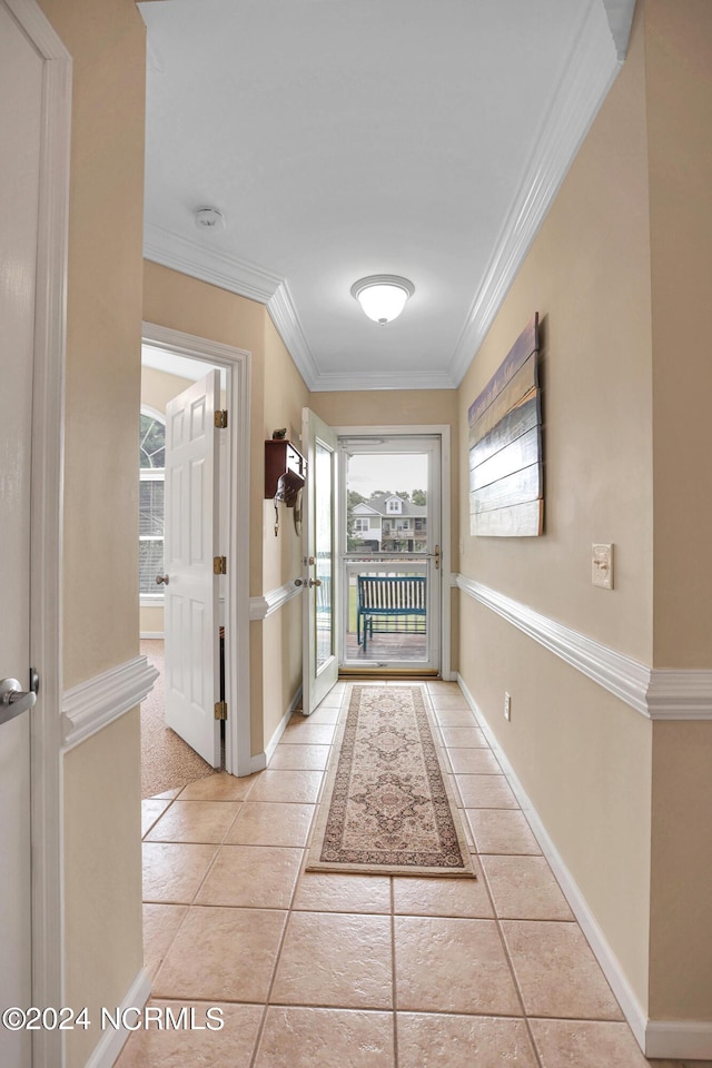 doorway featuring ornamental molding, light tile patterned flooring, and baseboards