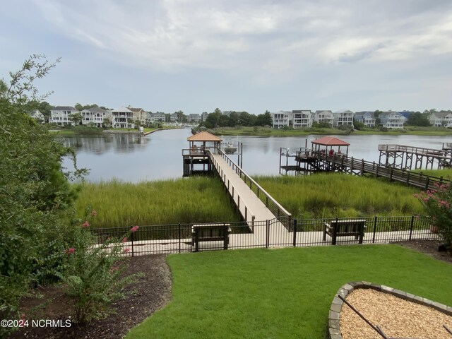 view of dock with a yard and a water view