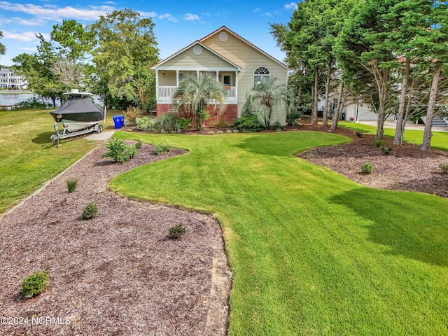 view of front of home with covered porch, brick siding, and a front yard