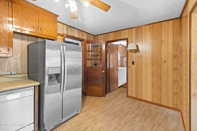 kitchen featuring stainless steel fridge with ice dispenser, light hardwood / wood-style floors, white dishwasher, ceiling fan, and wooden walls