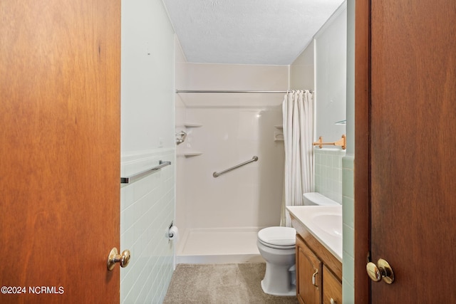 bathroom with a textured ceiling, tile walls, a shower with curtain, and vanity