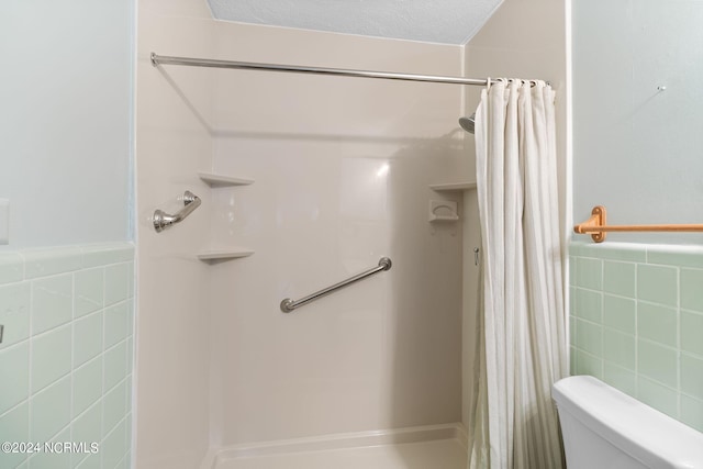 bathroom featuring a shower with shower curtain, tile walls, and toilet