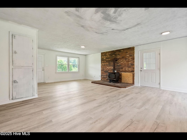 9348 NC Highway 210, Rocky Point, NC 28457 - unfurnished living room featuring a wood stove, light wood finished floors, a textured ceiling, and baseboards