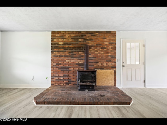 9348 NC Highway 210, Rocky Point, NC 28457 - unfurnished living room featuring a wood stove, wood finished floors, baseboards, and a textured ceiling