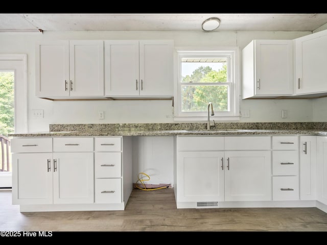 9348 NC Highway 210, Rocky Point, NC 28457 - kitchen with a sink, white cabinets, light stone countertops, and light wood finished floors