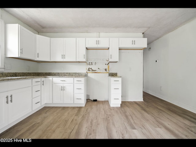 9348 NC Highway 210, Rocky Point, NC 28457 - kitchen featuring light wood-type flooring, white cabinetry, light stone counters, and baseboards