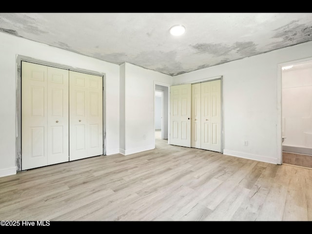 9348 NC Highway 210, Rocky Point, NC 28457 - unfurnished bedroom featuring two closets, light wood-style floors, baseboards, and ensuite bathroom