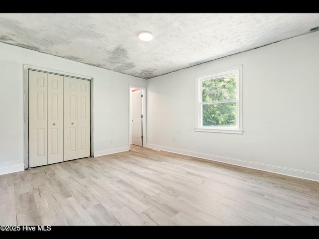 9348 NC Highway 210, Rocky Point, NC 28457 - unfurnished bedroom with light wood-style flooring, baseboards, a textured ceiling, and a closet