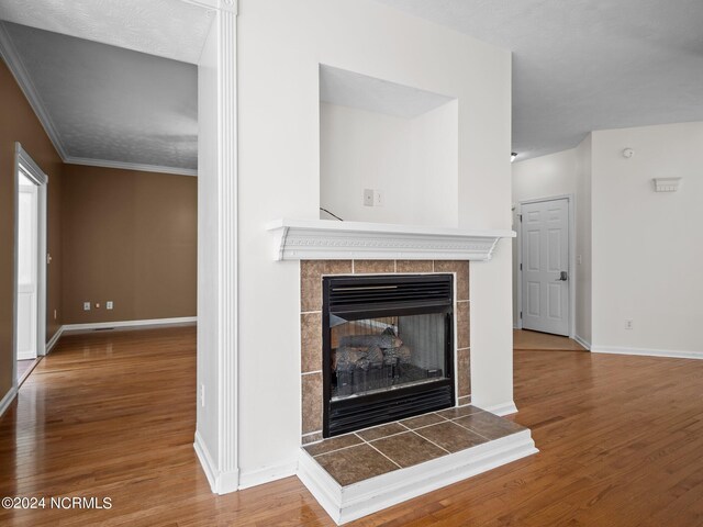 unfurnished living room with hardwood / wood-style flooring, crown molding, and a tile fireplace