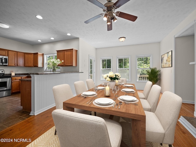 dining room with a textured ceiling, ceiling fan, and dark hardwood / wood-style flooring