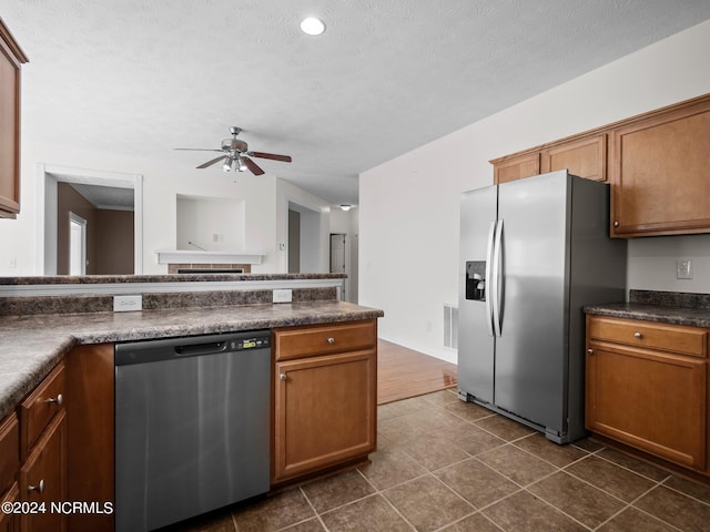 kitchen featuring a textured ceiling, dark tile patterned floors, ceiling fan, and stainless steel appliances