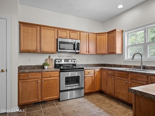 kitchen featuring stainless steel appliances, sink, and dark tile patterned floors