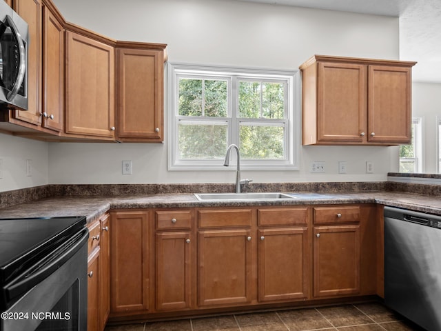 kitchen with stainless steel appliances, sink, dark tile patterned floors, and a wealth of natural light