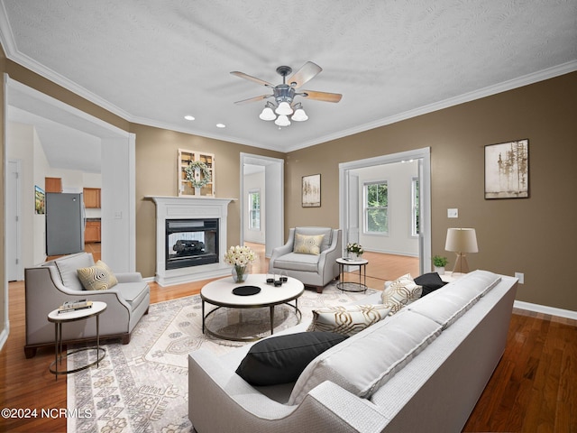 living room with a multi sided fireplace, ceiling fan, hardwood / wood-style floors, and a textured ceiling