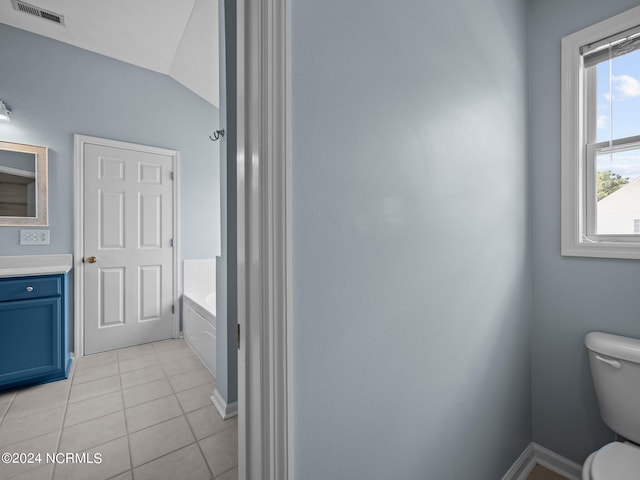 bathroom with toilet, vaulted ceiling, tile patterned floors, vanity, and a bathing tub