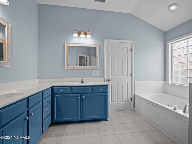 bathroom featuring vanity, a washtub, a textured ceiling, tile patterned floors, and vaulted ceiling