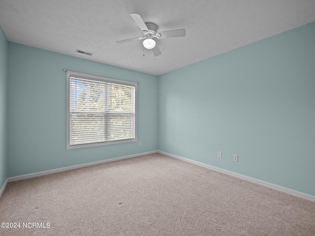 empty room featuring ceiling fan and carpet