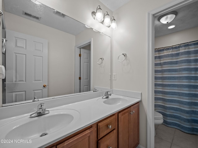 bathroom with curtained shower, vanity, a textured ceiling, toilet, and tile patterned floors