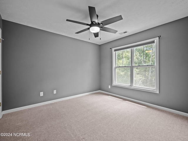 carpeted empty room featuring ceiling fan and a textured ceiling