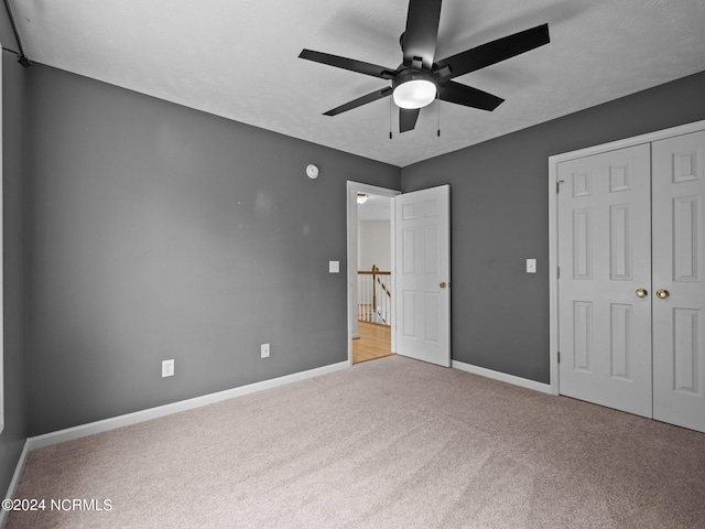 unfurnished bedroom featuring ceiling fan, light colored carpet, and a closet