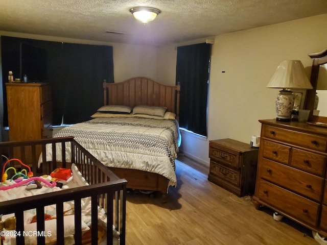 bedroom featuring a textured ceiling and light hardwood / wood-style flooring